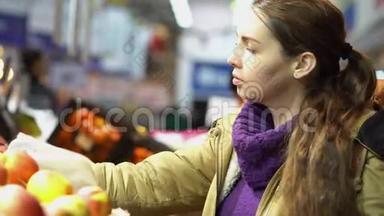 年轻漂亮的孕妇在超市挑选新鲜的有机苹果